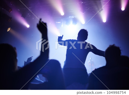 Rock concert, dance and party crowd with disco lighting and people back with dancing. Silhouette, audience and night festival event with performance and group listening and watching a band music 104998754