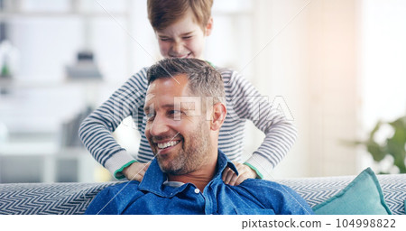 Love, father and son happy smile in living room of their home with lens flare. Happiness or caring, family and male parent with child playing spending quality time or bonding together on couch 104998822