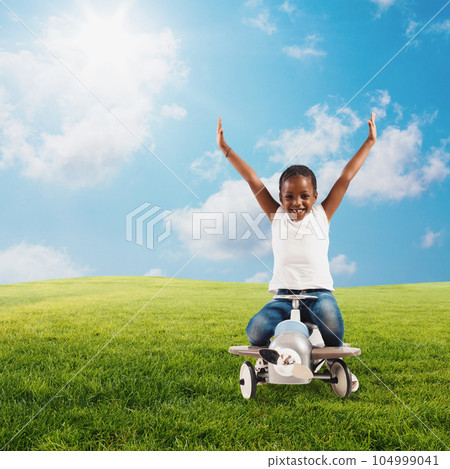 Young girl plays with an airplane toy in a green field 104999041