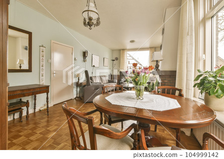 a dining room with wood flooring and wooden table in front of large window looking out onto the living room 104999142