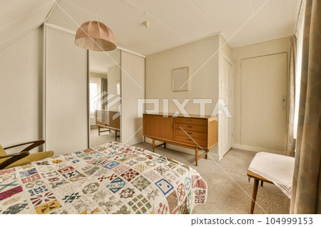 a bedroom with a bed, dresser and mirror on the wall behind it is a chair that has been used for storage 104999153