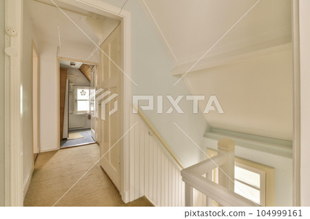 a long hallway with white trim on the walls, and carpeted stairs leading up to an open door that leads to another room 104999161