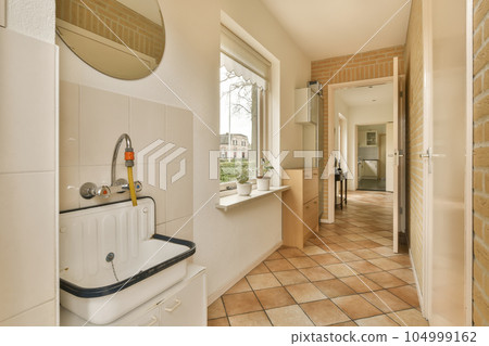 a bathroom with tile flooring and white fixtures on the wall behind it is a sink, mirror and window 104999162