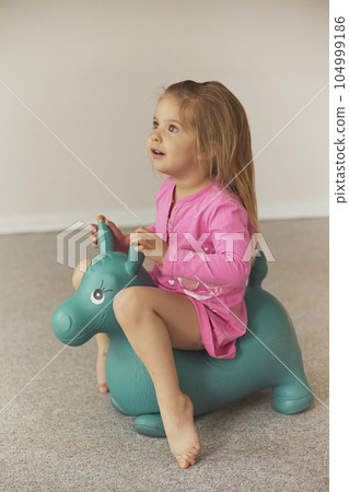Adorable child on a toy horse at home Adorable child on a toy horse at home 104999186