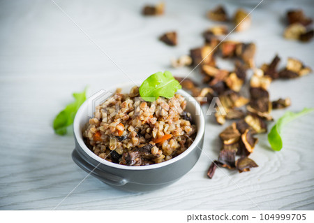 boiled buckwheat with vegetables and dried forest mushrooms in a ceramic mold 104999705