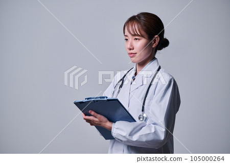 A young female doctor in a white coat who treats with a binder 105000264