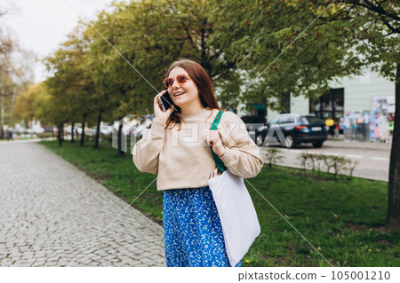 Outdoor lifestyle fashion portrait of woman talking on phone on the street. Close up of woman using smartphone outdoors. Urban lifestyle concept Outdoor lifestyle fashion portrait of woman talking on phone on the street. Close up of woman using smartphone outdoors. Urban lifestyle concept 105001210