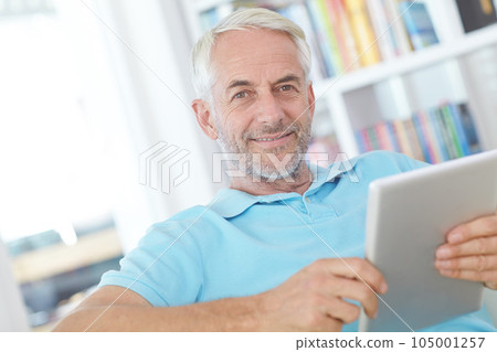 Tablet, portrait or relax senior man doing internet, web or online website search while happy in home living room. Online shopping, digital tech or elderly person typing, check or scroll on ui screen Tablet, portrait or relax senior man doing internet, web or online website search while happy in home living room. Online shopping, digital tech or elderly person typing, check or scroll on ui screen 105001257