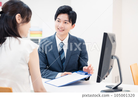 男工作人員在窗口聆聽顧客的要求 男工作人員在窗口聆聽顧客的要求 105001320