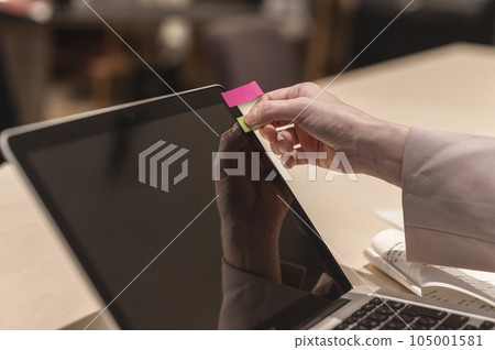 女人的手在筆記本電腦上貼一張便利貼 105001581
