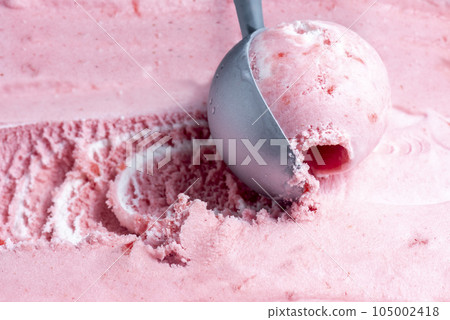 Pink strawberry ice cream is scooped up with a spoon 105002418