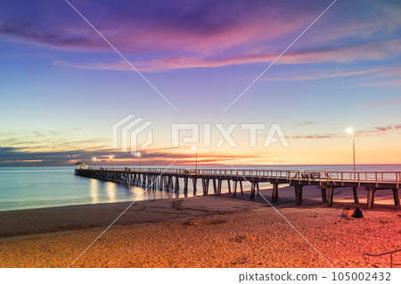 Henley Beach jetty at dusk with the tranquil sea embracing the weathered pillars with purple cluds above, South Australia Henley Beach jetty at dusk with the tranquil sea embracing the weathered pillars with purple cluds above, South Australia 105002432