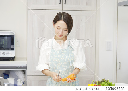 廚房裡用削皮器削胡蘿蔔的女人 廚房裡用削皮器削胡蘿蔔的女人 105002531