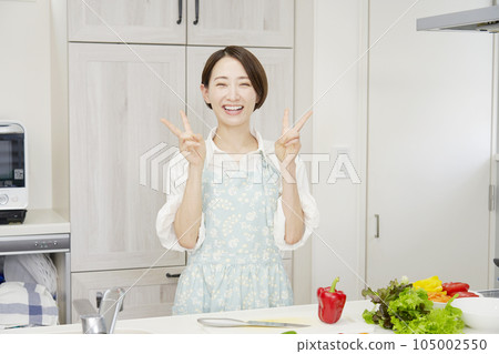 中年婦女在廚房裡做和平手勢 105002550