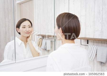 Middle-aged woman doing skin care in the washroom 105002563