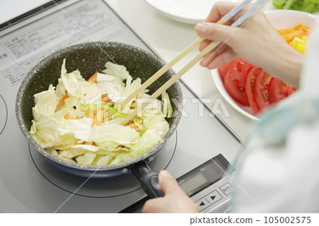 Woman stir-frying vegetables at home faceless Woman stir-frying vegetables at home faceless 105002575