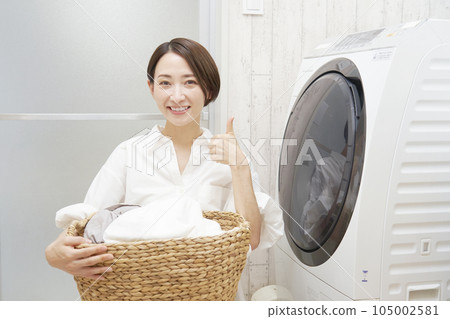 一位中年婦女在洗衣機前拿著洗好的衣服擺好姿勢 一位中年婦女在洗衣機前拿著洗好的衣服擺好姿勢 105002581