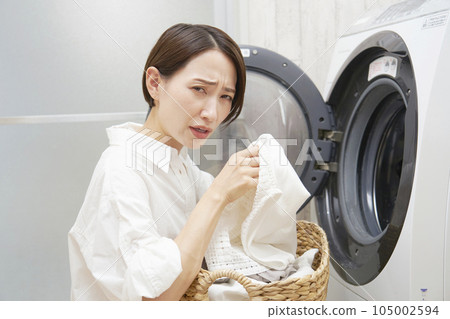一名中年婦女因洗衣機前的衣物氣味而煩惱 一名中年婦女因洗衣機前的衣物氣味而煩惱 105002594