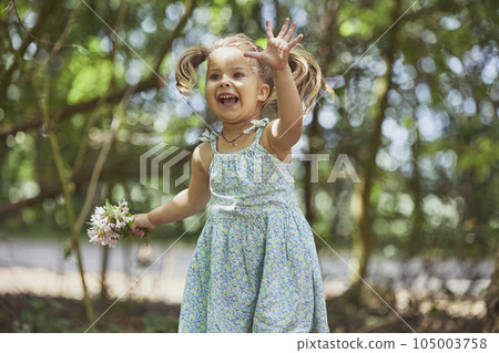 charming child in sundress with a bouquet of flowers in the garden 105003758