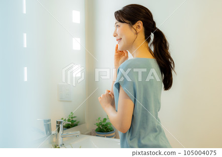 A woman looking at a mirror in the washroom 105004075