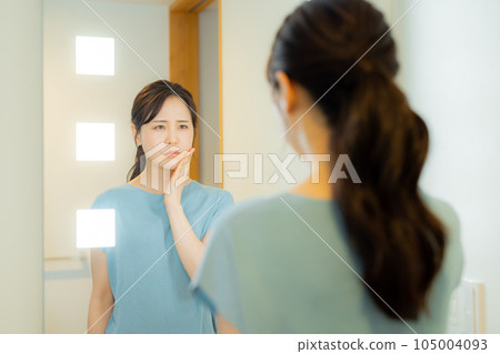 A woman looking at a mirror in the washroom A woman looking at a mirror in the washroom 105004093