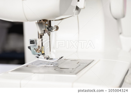 Modern white sewing machine presser foot closeup, macro Modern white sewing machine presser foot closeup, macro 105004324