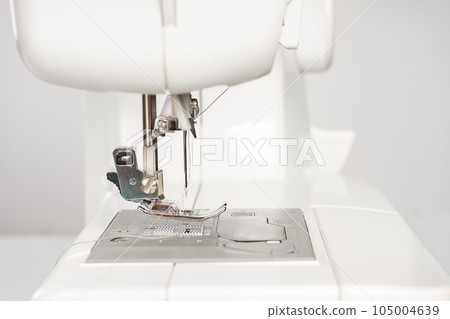 Modern white sewing machine presser foot closeup, macro 105004639