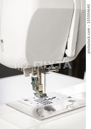 Modern white sewing machine presser foot closeup, macro 105004640