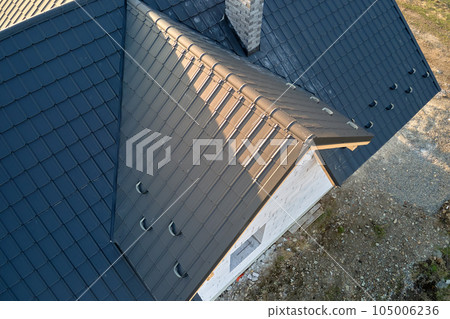 Aerial view of unfinished house with aerated lightweight concrete walls and wooden roof frame covered with metallic tiles under construction. Aerial view of unfinished house with aerated lightweight concrete walls and wooden roof frame covered with metallic tiles under construction. 105006236