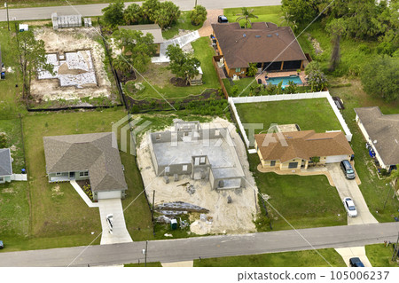 Aerial view of unfinished frame of private house with brick concrete walls ready for mounting wooden roof beams under construction Aerial view of unfinished frame of private house with brick concrete walls ready for mounting wooden roof beams under construction 105006237