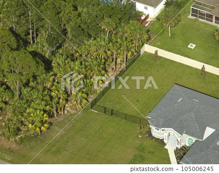 Aerial view of typical contemporary american private house with roof top covered with asphalt shingles and green lawn on yard 105006245