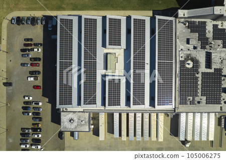 Aerial view of solar power plant with blue photovoltaic panels mounted on industrial building roof for producing green ecological electricity. Production of sustainable energy concept Aerial view of solar power plant with blue photovoltaic panels mounted on industrial building roof for producing green ecological electricity. Production of sustainable energy concept 105006275