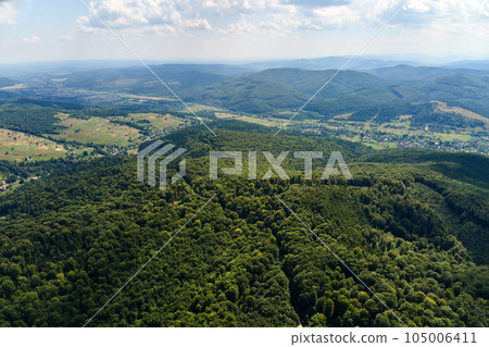 Aerial view of mountain hills covered with dense green lush woods on bright summer day. Aerial view of mountain hills covered with dense green lush woods on bright summer day. 105006411