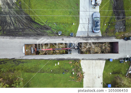 Aerial view of Hurricane Ian special aftermath recovery dump truck picking up vegetation debris from Florida suburban streets. Dealing with consequences of natural disaster 105006450