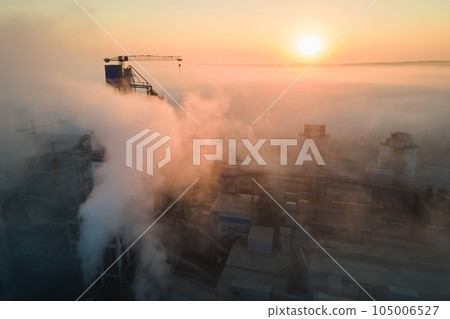 Aerial view of cement factory with high concrete plant structure and tower crane at industrial manufacturing site on foggy evening. Production and global industry concept. Aerial view of cement factory with high concrete plant structure and tower crane at industrial manufacturing site on foggy evening. Production and global industry concept. 105006527