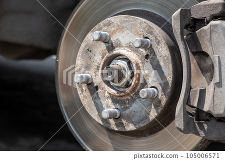Disc brake of the vehicle for repair, in process of new tire replacement. Car brake repairing in garage. Replacement of brake pads. Suspension of car for maintenance brakes and shock absorber systems. 105006571