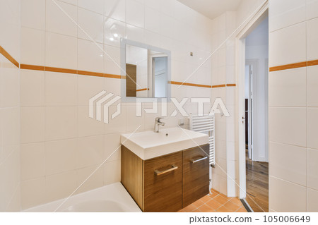 a bathroom with white tiles on the walls and wood trim around the tub, sink, and mirror in it 105006649