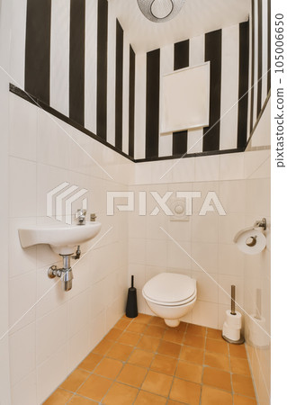 a bathroom with black and white stripes on the walls, two sinks and one toilet in the floor is tiled 105006650