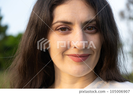 Portrait of a 35-year-old brunette woman looking at the camera smiling in nature. Portrait of a 35-year-old brunette woman looking at the camera smiling in nature. 105006907