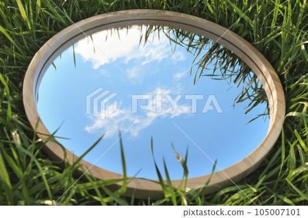 Cloudy Blue Sky Reflection in Round Wood Mirror on Summer Field with Green Grass. Nature Concept. Earth Day. Save Environment. Peace. Ecology Protection. Climate Change, Global Warming Effect Problem Cloudy Blue Sky Reflection in Round Wood Mirror on Summer Field with Green Grass. Nature Concept. Earth Day. Save Environment. Peace. Ecology Protection. Climate Change, Global Warming Effect Problem 105007101