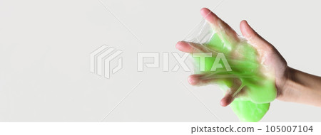 Hand Playing with textured slime on white background. Teen hand holding green shining slime with bubbles, stretching gooey substance. Teenage Girl squeezing slime toy to the sides. Liquid toy. Handgum 105007104