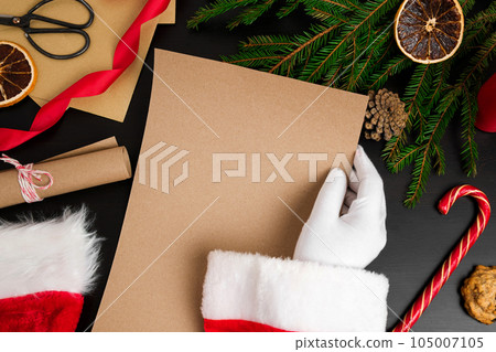 Santa Claus Reading Letters from Children on Desk. Top View of Jolly Father Hands Holding a Blank Brown Paper Page. View from Above of Wood Table with Ornament, Christmas Decoration. Letter Mock Up Santa Claus Reading Letters from Children on Desk. Top View of Jolly Father Hands Holding a Blank Brown Paper Page. View from Above of Wood Table with Ornament, Christmas Decoration. Letter Mock Up 105007105