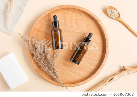 Amber glass dropper cosmetic bottle, white podium. Natural skin care SPA beauty product design. Mineral organic oil on pink background. Mock-Up. Oily pipette. Face and body treatment. Front view 105007308