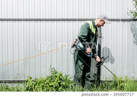 a man mows lawn grass with a lawn mower. petrol lawn mower, trimmer close-up. Man working in the garden 105007717