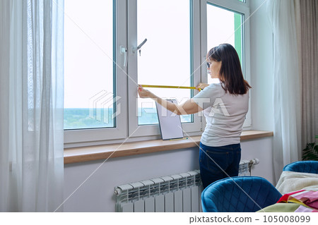 Woman measuring window with tape measure, tailoring service Woman measuring window with tape measure, tailoring service 105008099