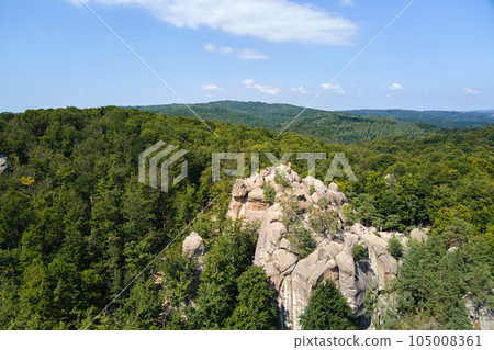 Aerial view of bright landscape with green forest trees and big rocky boulders between dense woods in summer. Beautiful scenery of wild woodland. Aerial view of bright landscape with green forest trees and big rocky boulders between dense woods in summer. Beautiful scenery of wild woodland. 105008361