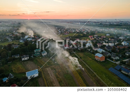 Aerial view of agricultural waste bonfires from dry grass and straw stubble burning with thick smoke polluting air during dry season on farmlands causing global warming and carcinogen fumes Aerial view of agricultural waste bonfires from dry grass and straw stubble burning with thick smoke polluting air during dry season on farmlands causing global warming and carcinogen fumes 105008402