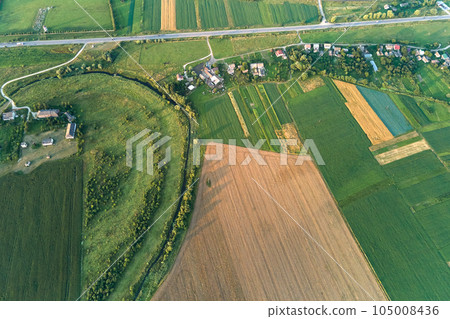 Aerial landscape view of green and yellow cultivated agricultural fields with growing crops on bright summer day 105008436