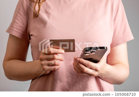 Berlin, Germany July 15 2023 hands with bank card and mobile phone, paying online with plastic Berlin, Germany July 15 2023 hands with bank card and mobile phone, paying online with plastic 105008710