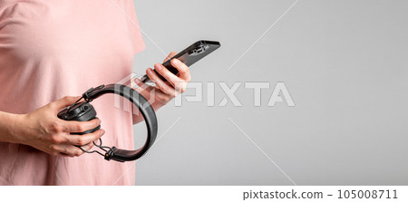 Berlin Germany July 07 2023 Hand holding mobile phone, headphones. Banner background 105008711